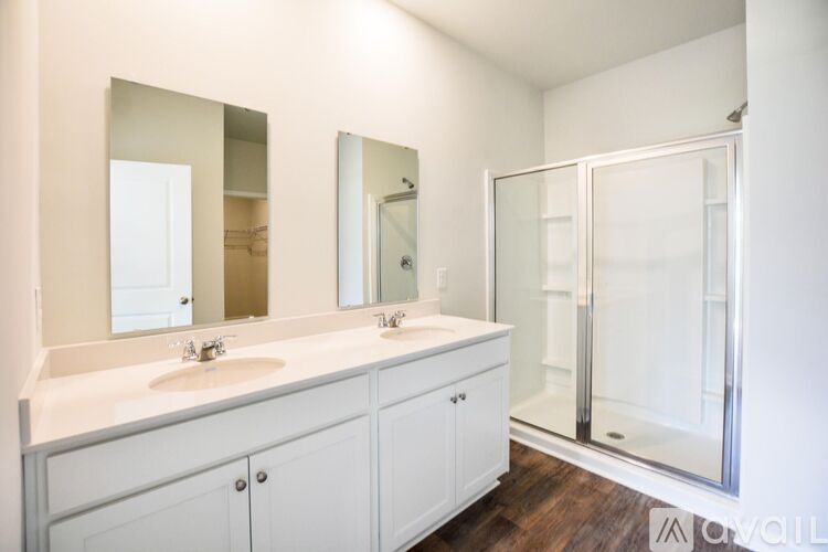 A white bathroom with a double sink and a walk-in shower.