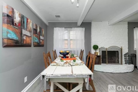 A dining room with a white table and chairs, a fireplace, and a painting on the wall.