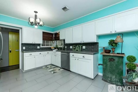 A kitchen with white cabinets and a black countertop.