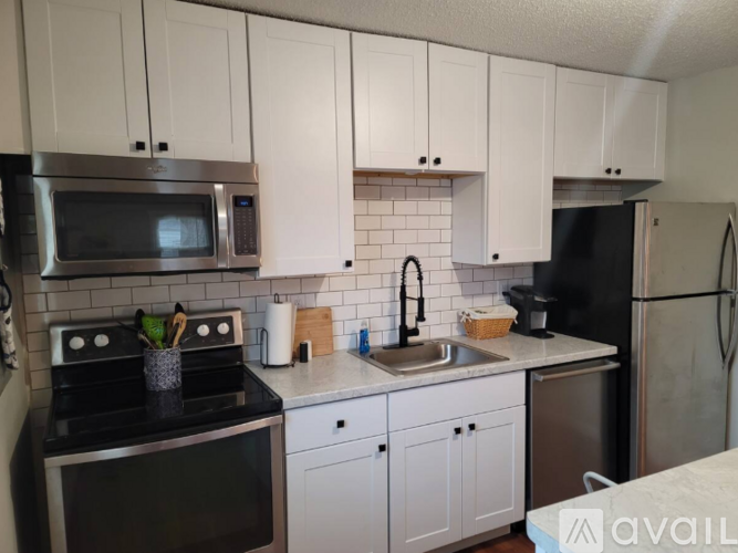 A kitchen with white cabinets and black appliances.
