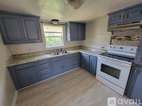 A kitchen with a white stove top oven and a window.