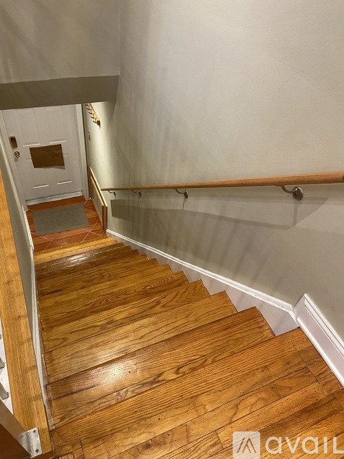 A wooden staircase with a white wall and a white door at the top.