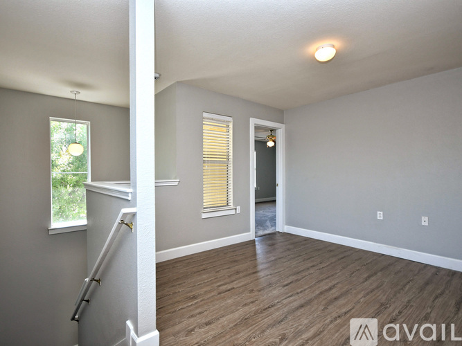 A spacious room with wooden flooring and a staircase leading to another level.