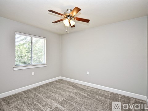 A room with a ceiling fan and a window with blinds.