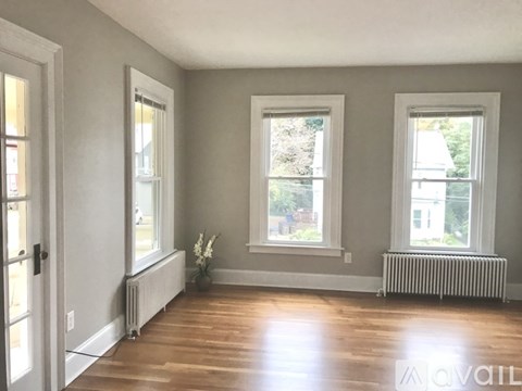 A room with wooden floors and three windows.