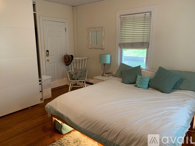 A bedroom with a white bed and a window with blinds.