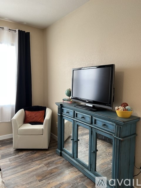 A black television is on a green cabinet in a living room.