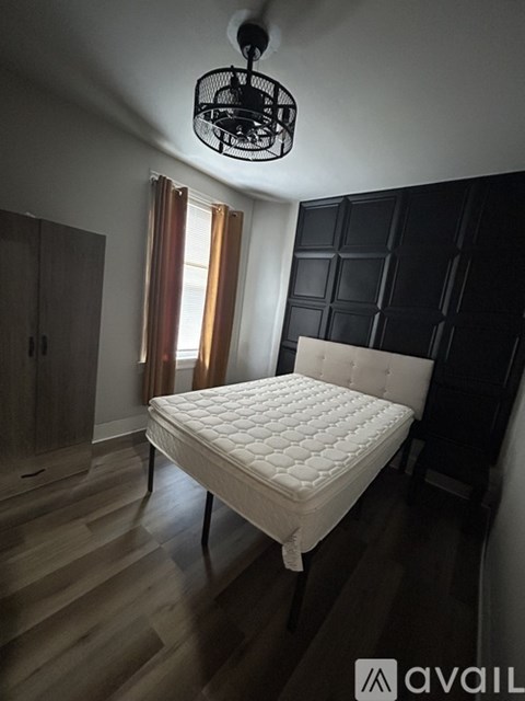 A bedroom with a white bed and wooden floors.