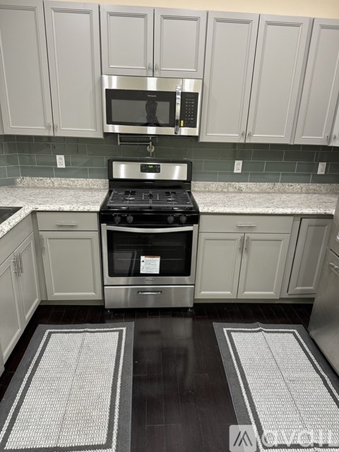 A kitchen with a black stove top oven and a microwave above it.