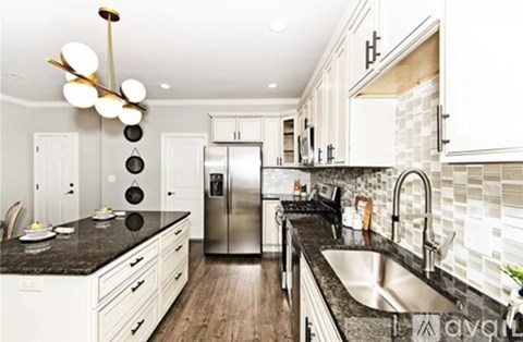 A modern kitchen with a granite countertop and stainless steel appliances.