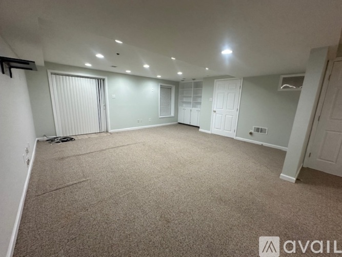 A spacious room with carpeted floor and white walls.
