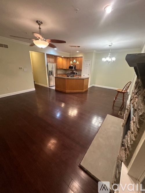 A living room with a kitchen in the background and a wood floor.