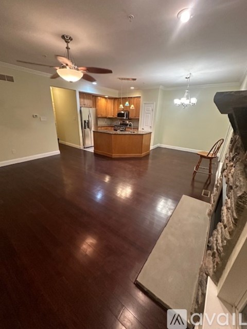 A living room with a kitchen in the background and a wood floor.