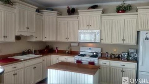 A kitchen with white cabinets and a wooden island.