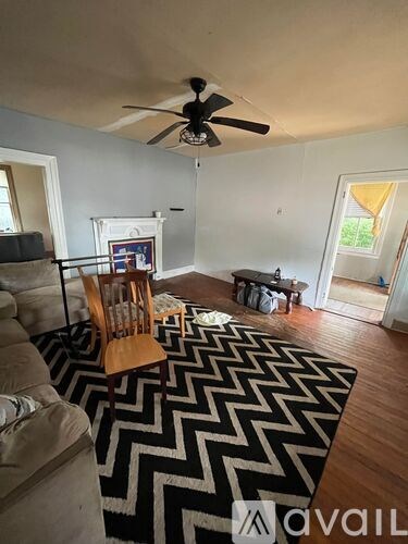A living room with a black and white rug and a ceiling fan.