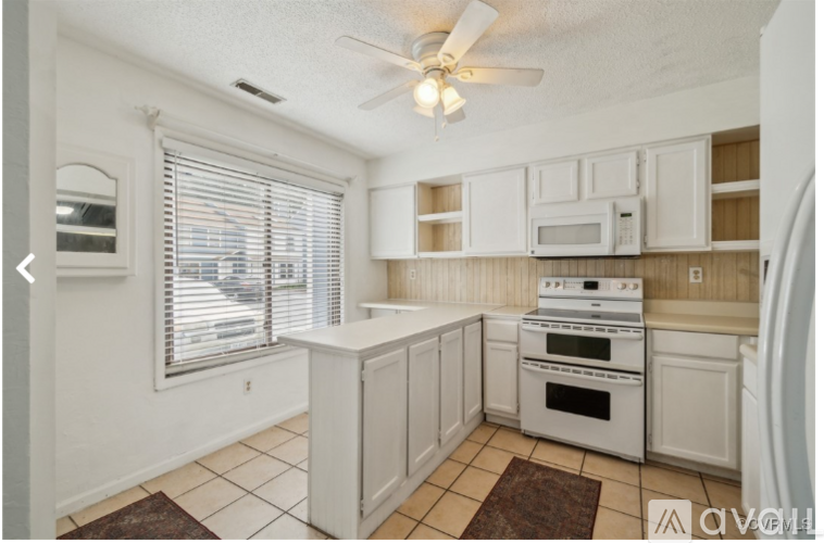 A kitchen with white cabinets and a white stove top oven.