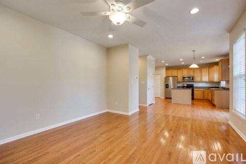 A spacious living room with hardwood floors and a ceiling fan.