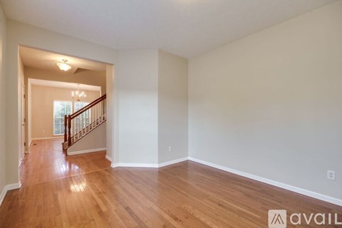 A spacious room with wooden floors and a staircase leading to another room.