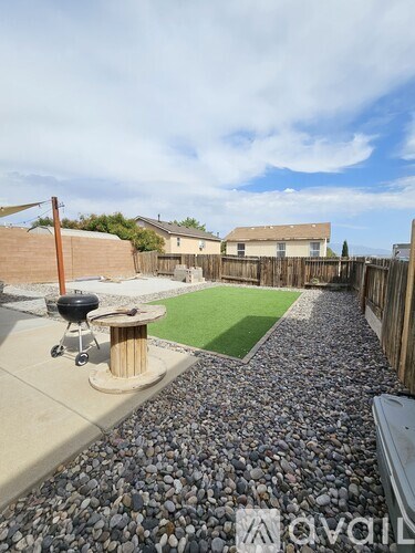 A backyard with a BBQ grill and a gravel path.