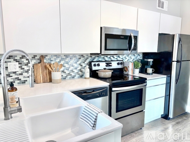 A kitchen with a white sink and black countertops.