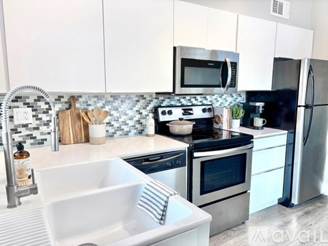 A kitchen with a white sink and black countertops.