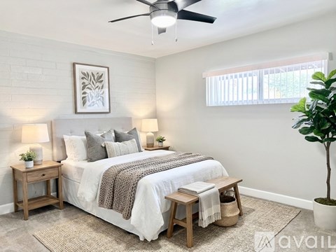 A bedroom with a bed, a ceiling fan, and a potted plant.