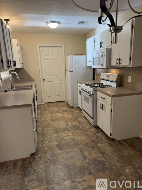 A kitchen with a stove, refrigerator, and cabinets.