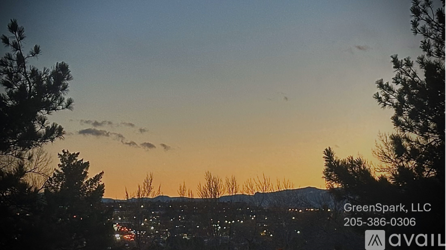 A sunset view with trees and a cityscape in the distance, with the text "GreenSpark, LLC" and a phone number overlaying the image.