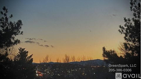 A sunset view with trees and a cityscape in the distance, with the text "GreenSpark, LLC" and a phone number overlaying the image.