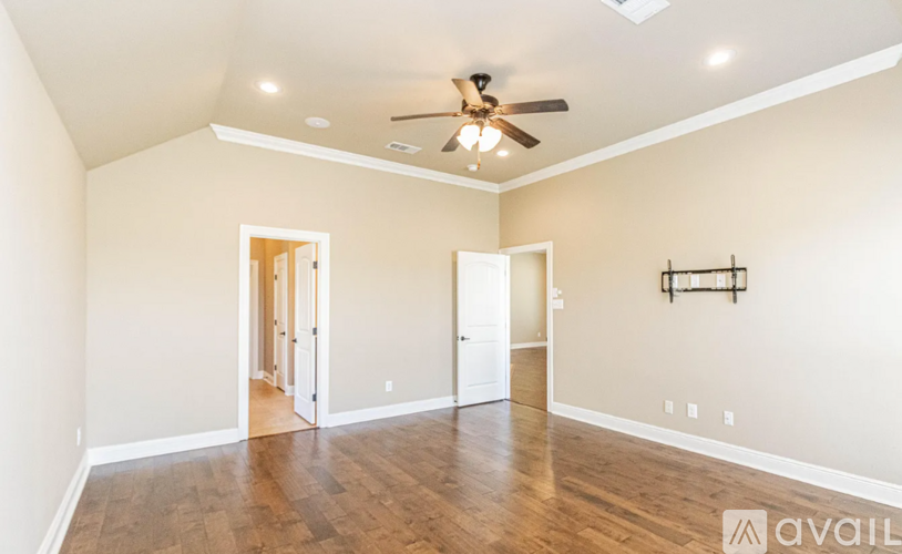 A spacious room with a ceiling fan and wooden flooring.