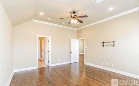 A spacious room with a ceiling fan and wooden flooring.