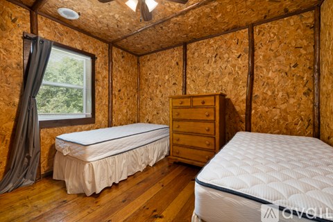 A bedroom with two beds, one with a white mattress and the other with a blue mattress.