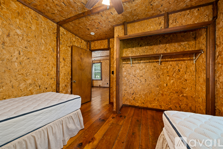 A bedroom with wooden walls and a ceiling fan.