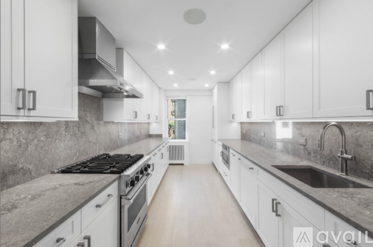 A modern kitchen with white cabinets and a marble countertop.