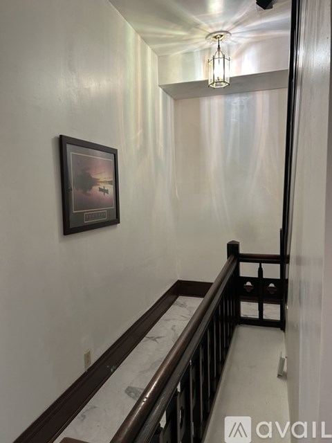 A picture of a sunset is hanging on a wall above a staircase.