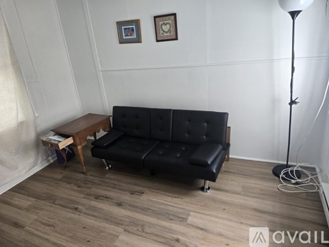 A black leather sofa with a wooden table in front of it.