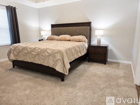 A bedroom with a bed, nightstand, and carpet.