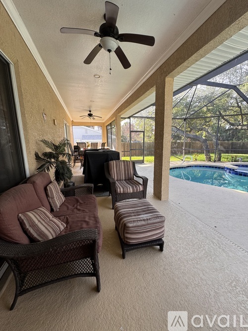 A patio with a ceiling fan and striped chairs.
