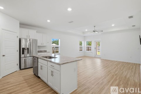 A kitchen with white cabinets and a wooden floor.