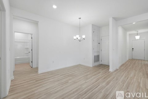 A spacious room with wooden flooring and white walls.