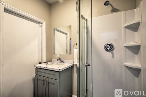 A bathroom with a sink, mirror, and shower.