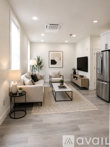 A modern living room with a white sofa, a black coffee table, and a TV on the wall.
