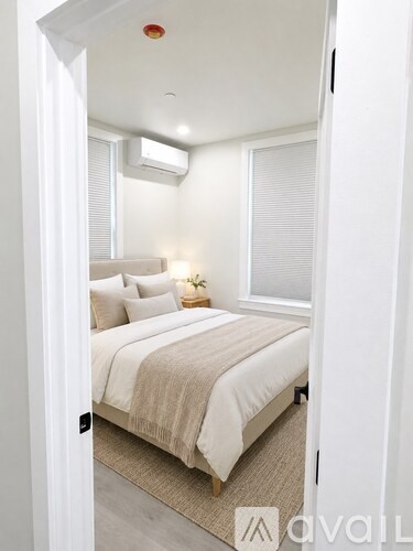 A bedroom with a bed, pillows, and a nightstand.