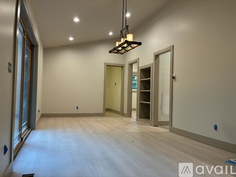 A spacious room with a chandelier and a doorway leading to another room.