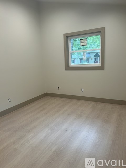 A room with a window showing a view of a house.