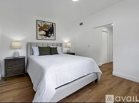 A bedroom with a large bed and a wooden floor.