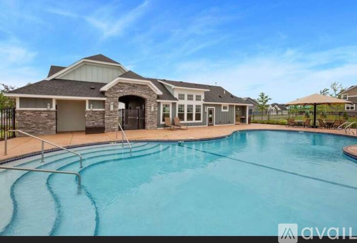 A large swimming pool in front of a house with a sign that says "available".