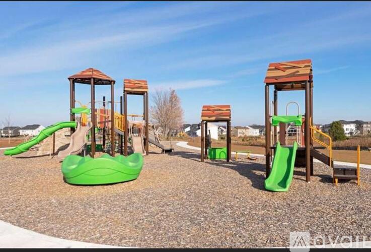 A playground with a green slide and wooden structures.