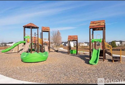 A playground with a green slide and wooden structures.