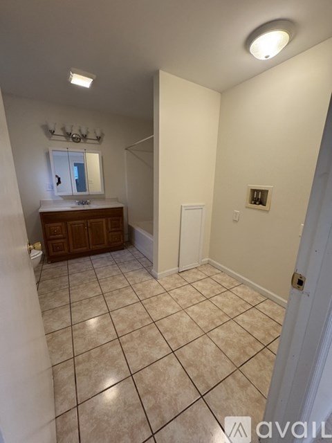 A bathroom with a tiled floor and a mirror above the sink.
